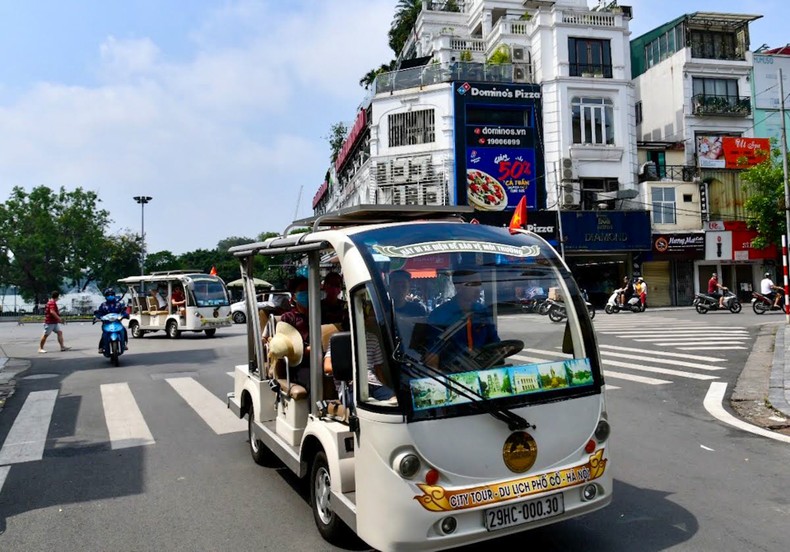 Khách du lịch tham quan khu phố cổ Hà Nội bằng xe điện.