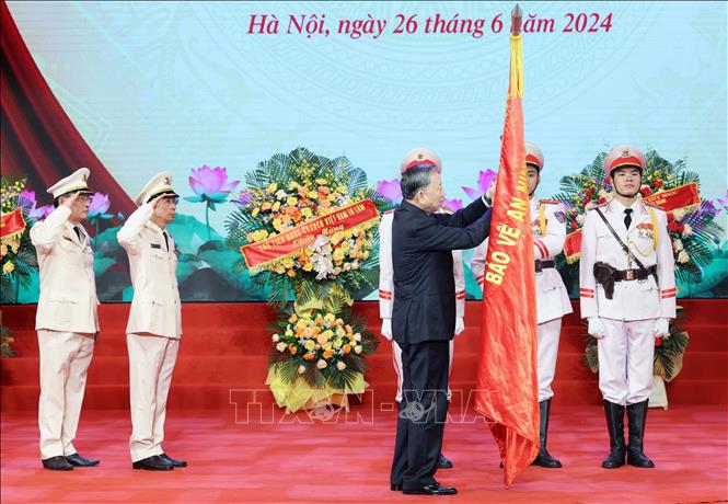 Chủ tịch nước gắn Huân chương Chiến công hạng Nhì lên cờ truyền thống của lực lượng Kỹ thuật nghiệp vụ CAND - Ảnh: TTXVN