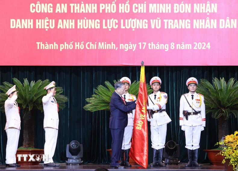 Tổng Bí thư, Chủ tịch nước Tô Lâm gắn Huy hiệu Anh hùng lực lượng vũ trang nhân dân lên lá cờ truyền thống của Công an Thành phố Hồ Chí Minh.