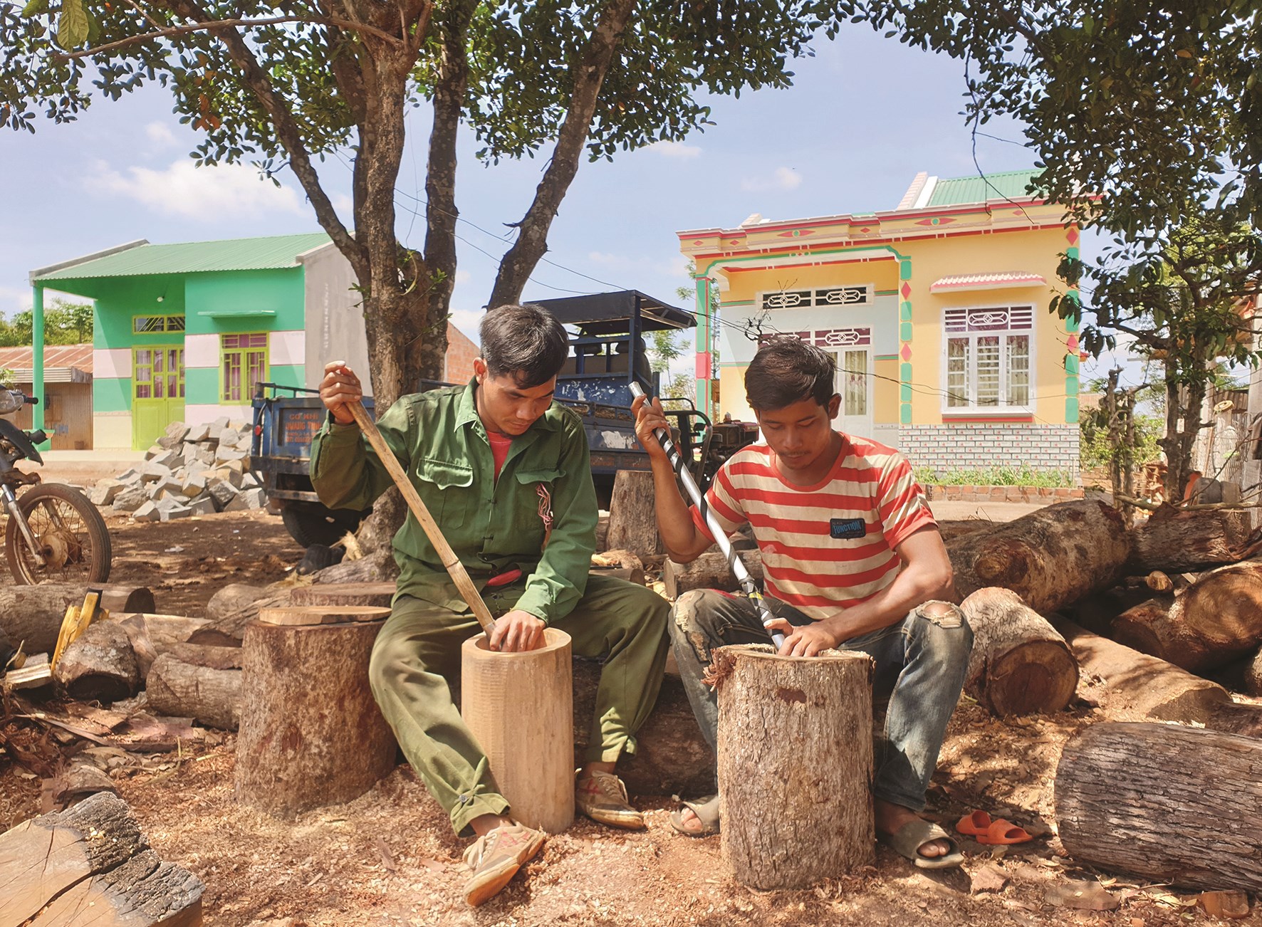 Anh Nhun (bên phải) và anh Thăng ( bên trái) đang miệt mài làm cối gỗ trước sân nhà.