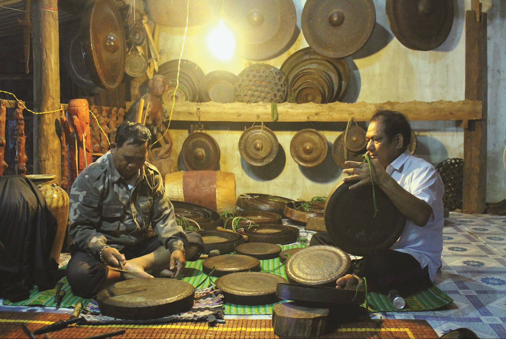  Nghệ nhân Ksor Hnao (bên phải) đang chỉnh chiêng, một nghề đang mất dần truyền nhân ở Tây Nguyên.