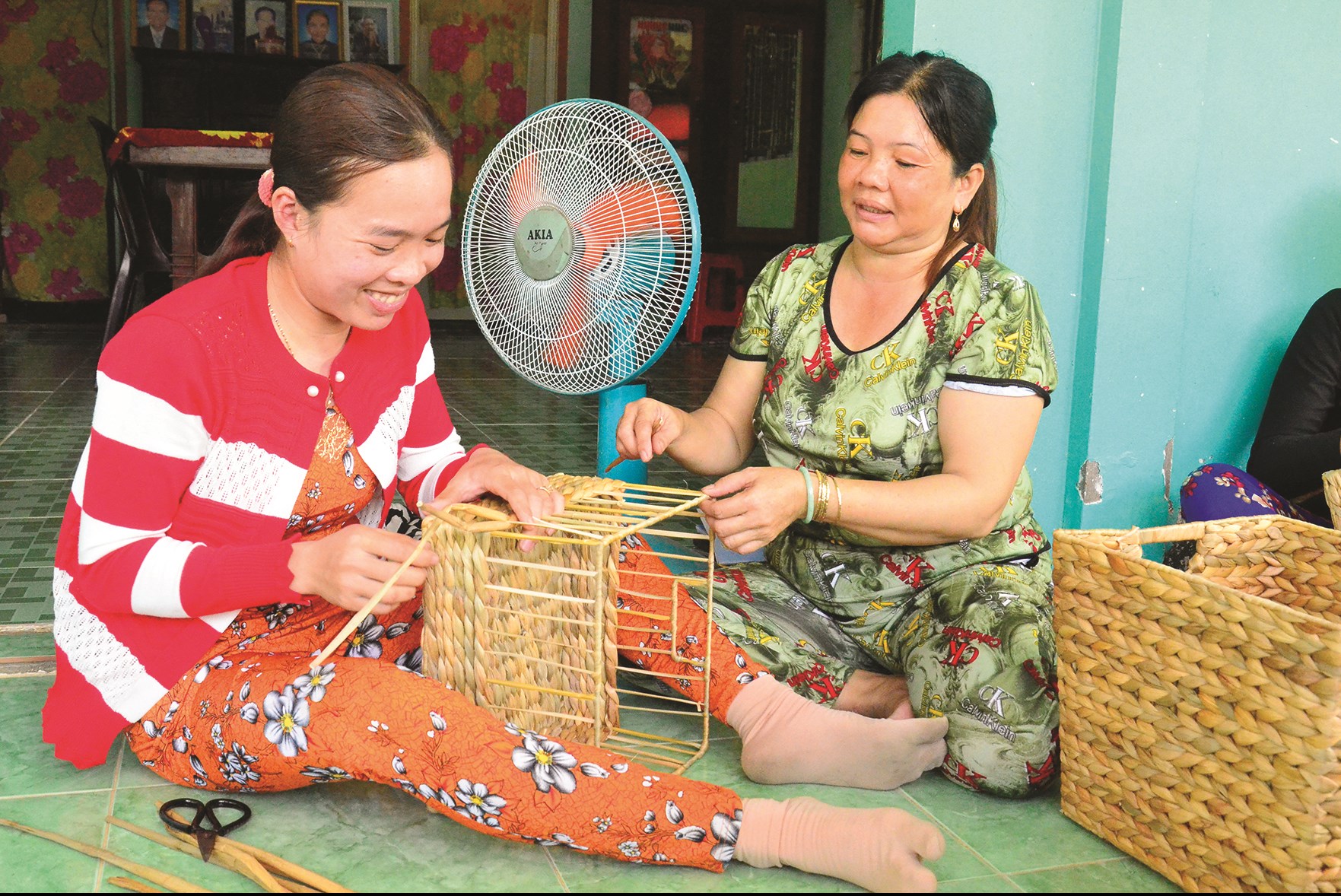 Chị Thị Kim Xuyền (bên phải), Tổ trưởng, hướng dẫn thành viên đan đát giỏ lục bình.