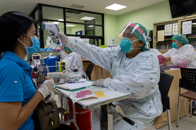 Một nhân viên y tế kiểm tra nhiệt độ cho bệnh nhân tại một bệnh viện ở tỉnh Nonthaburi, Thái Lan. (Ảnh: UN)