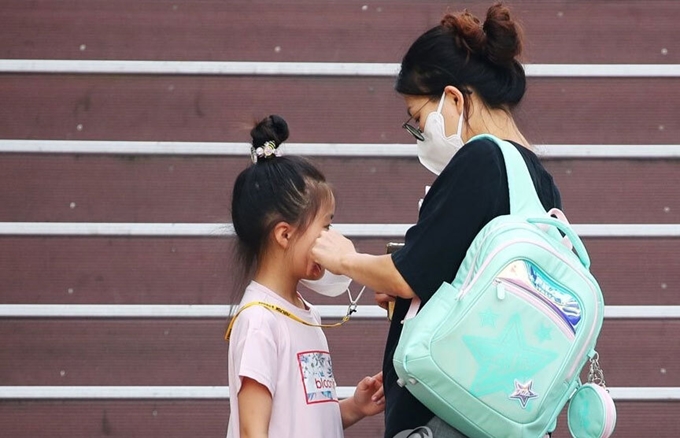 Một phụ huynh đeo khẩu trang cho con trước cổng trường tiểu học tại thủ đô Seoul, Hàn Quốc. (Ảnh: Yonhap) 