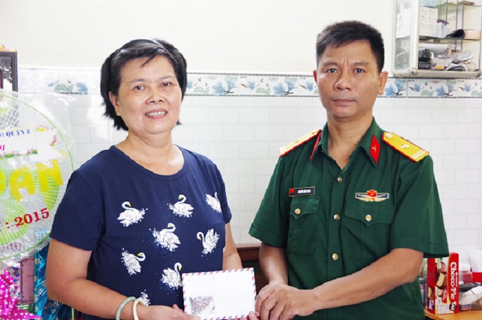 Thiếu tá Nguyễn Văn Vinh - Chính trị viên phó/Ban CHQS Quận 8 trao tặng phần quà cho gia đình.