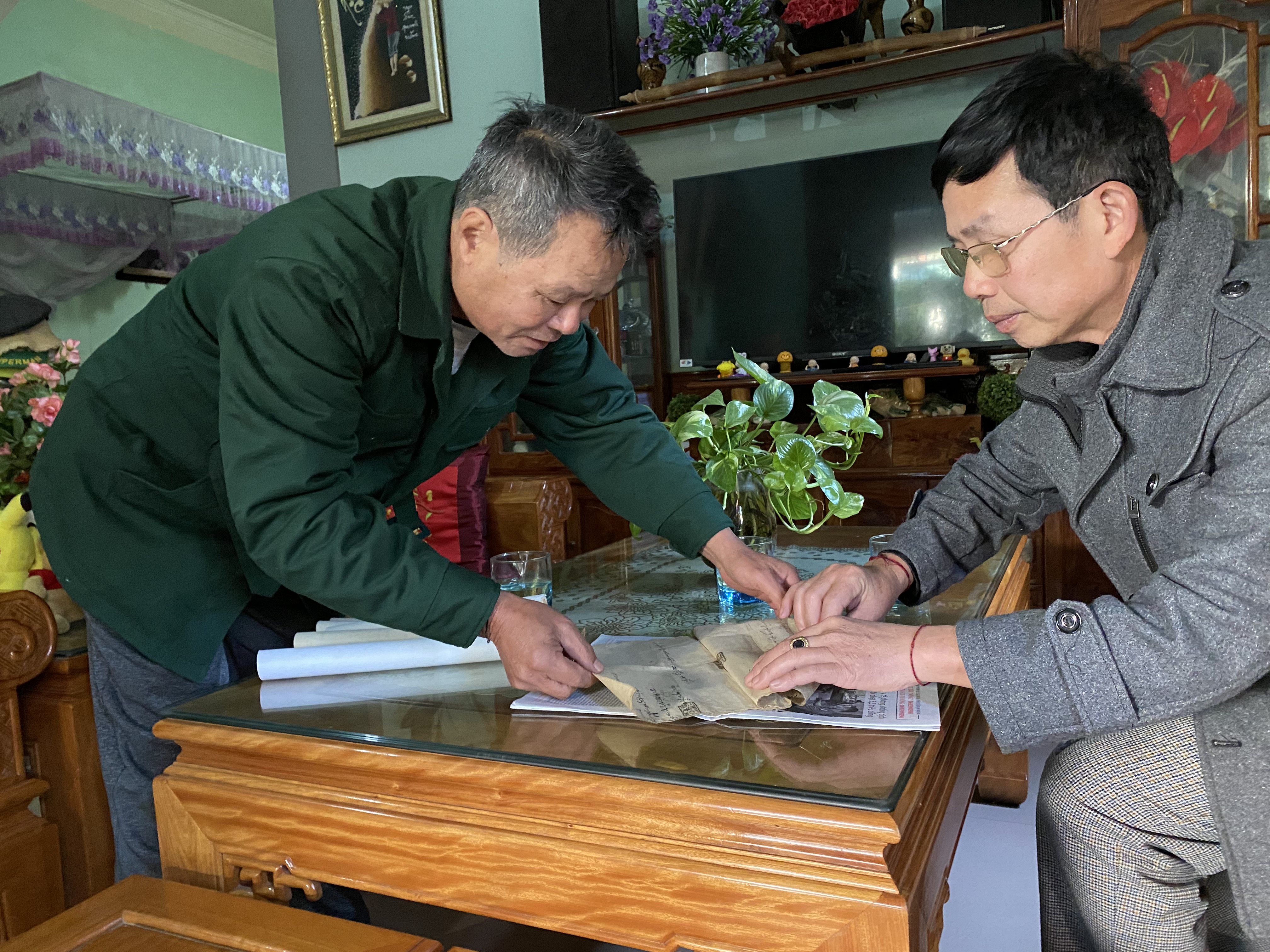 Ông Vi Tân Hợi (bìa phải) và thầy Lô Văn Thông giới thiệu về tờ khế ước cổ