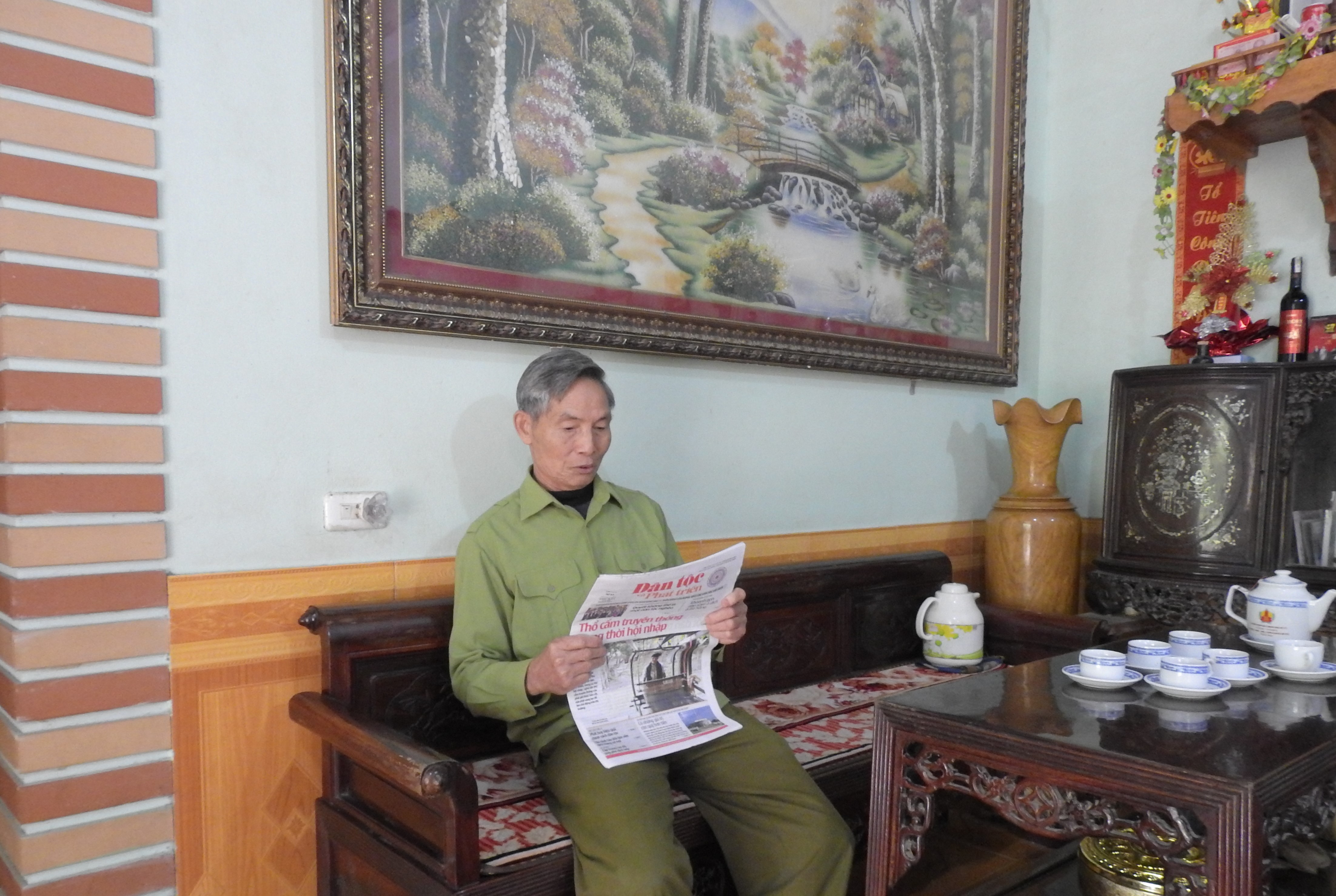 Người có uy tín Nguyễn Văn Huynh đọc Báo Dân tộc và Phát triển để học tập nhiều mô hình kinh tế hay chia sẻ lại với Nhân dân