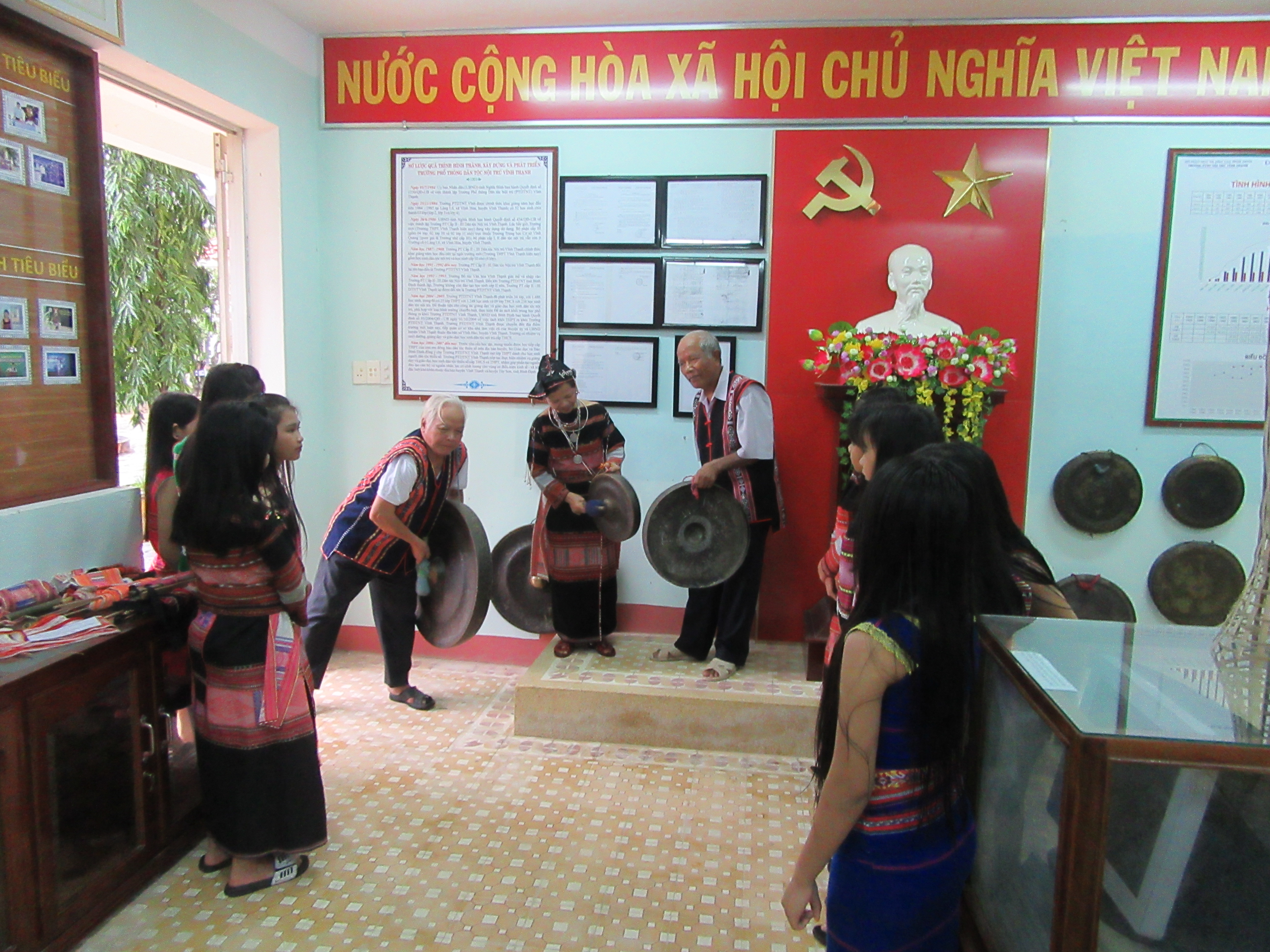 Các nghệ nhân hướng dẫn học sinh thuộc CLB Cồng chiêng thanh niên chơi nhạc cụ và múa xoang tại trường PTDTNT THCS và THPT Vĩnh Thạnh (huyện Vĩnh Thạnh).