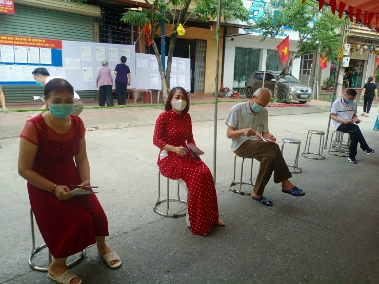 Các cử tri đi bỏ phiếu tại huyện Tràng Định được bố trí ghế ngồi giữ khoảng cách trong khi chờ tới lượt bầu cử