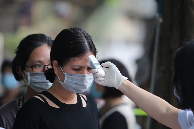 Nhân viên y tế đo thân nhiệt, ghi chép tình hình sức khoẻ của người dân phường Trúc Bạch. Ảnh: Lê Phú/Báo Tin tức