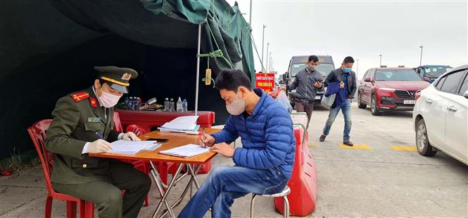 Lực lượng chức năng làm nhiệm vụ hướng dẫn, phân luồng giao thông, khai báo y tế tại chốt trạm cầu Bạch Đằng, thị xã Quảng Yên. Ảnh: TTXVN