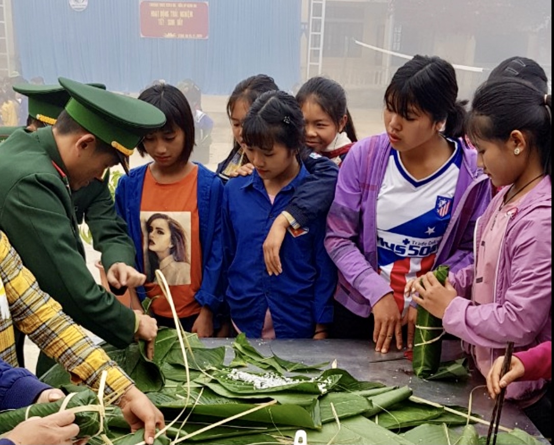 Các chú bộ đội hướng dẫn các cháu học sinh gói bánh chưng