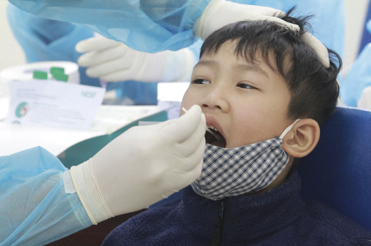 Học sinh trường Tiểu học Xuân Phương (Hà Nội) được nhân viên Trung tâm Y tế quận Nam Từ Liêm lấy dịch phết mũi và họng. Ảnh: Lê Phú.