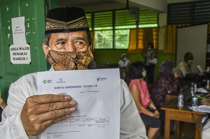 Một người dân xuất trình thẻ tiêm chủng vaccine COVID-19 ở Jakarta, Indonesia (Ảnh: The Jakarta Post)
