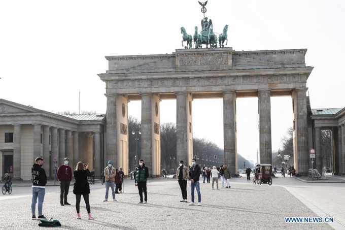 Khách bộ hành đeo khẩu trang khi chụp ảnh tại cổng Brandenburg ở thủ đô Berlin, Đức. (Ảnh: Xinhua)