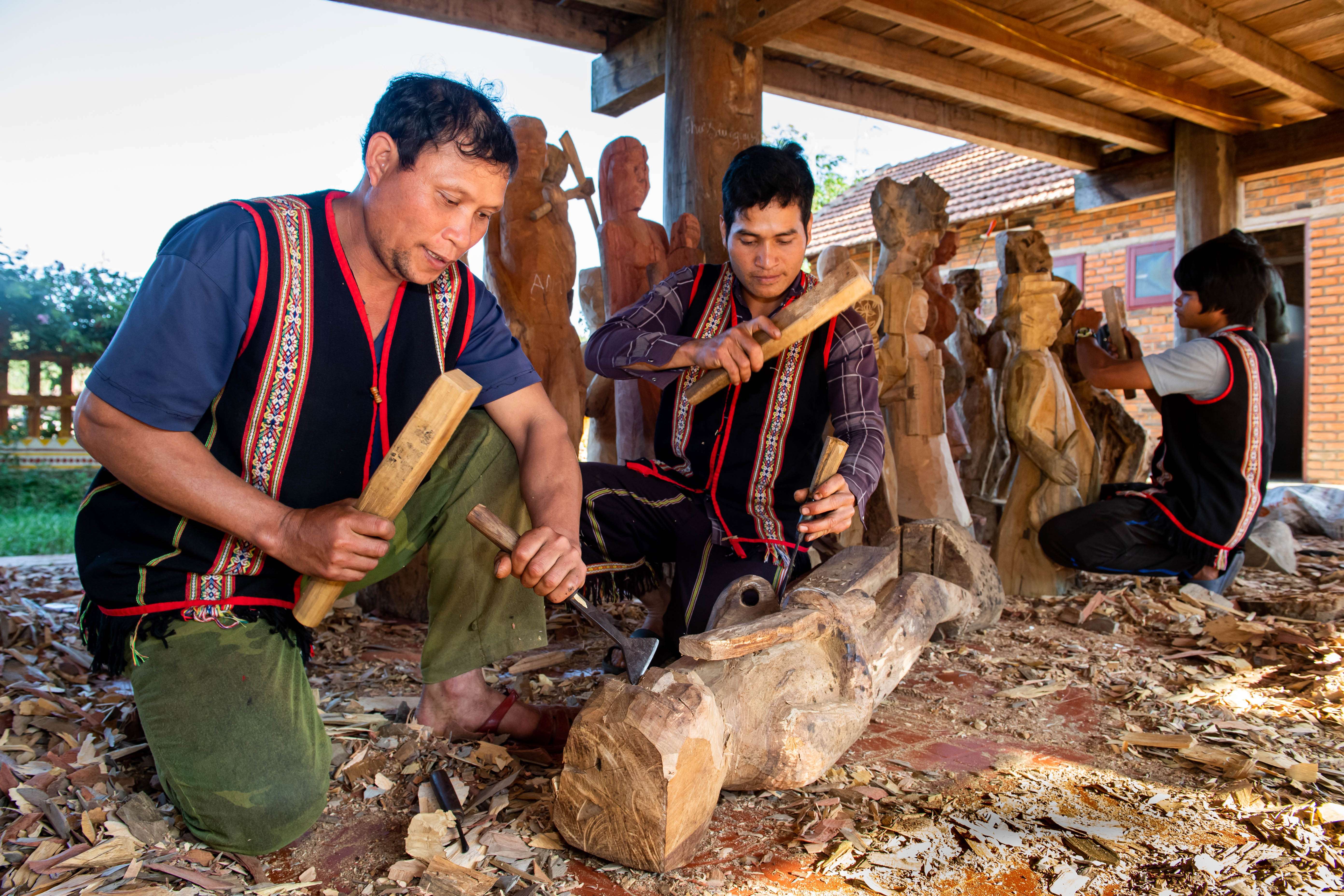Nghệ nhân ưu tú A Gông cùng các thanh niên trong làng Kon Du tạc tượng gỗ. Ảnh: Đ.T
