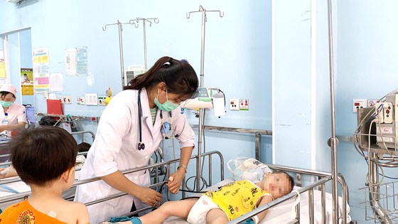 Bác sĩ Bệnh viện Nhi đồng 1 đang thăm khám và điều trị cho bệnh nhi mắc tay chân miệng. Ảnh: MINH NAM