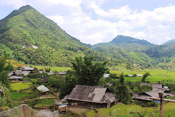 Con đường dẫn lên thôn uốn lượn xuyên qua màu xanh của ruộng nương cùng những mái nhà lúp xúp của đồng bào Dao