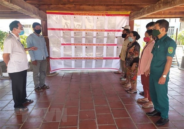 Chính quyền địa phương phối hợp với người uy tín trong thôn Kon Tum Kơ Pơng tuyên truyền bầu cử cho người dân, đồng thời đảm bảo an toàn trong bối cảnh dịch bệnh. (Ảnh: Dư Toán/TTXVN)