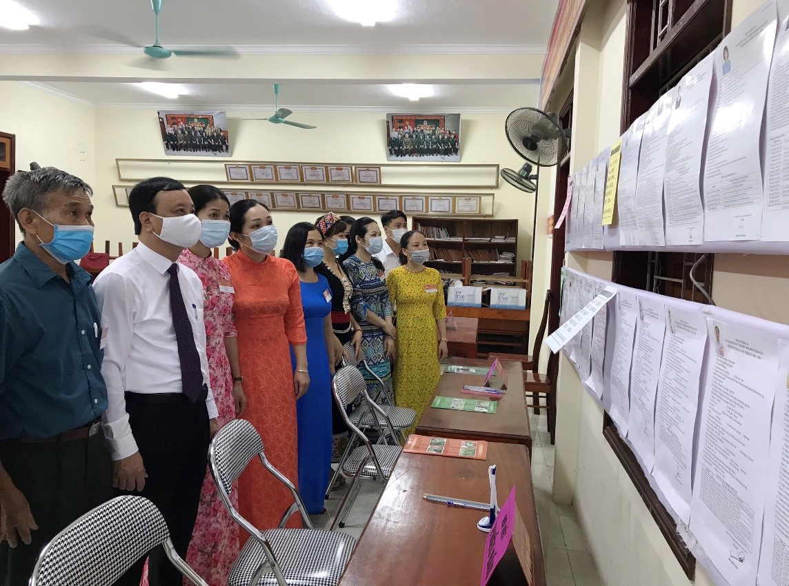 Đồng chí Nguyễn Văn Hải (áo trắng) cùng cử tri xem tiểu sử tóm tắt của các ứng cử viên trước khi tiến hành bầu cử
