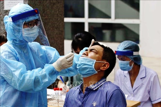 Sáng 4/6, nhân viên y tế lấy mẫu xét nghiệm COVID-19 cho người làm việc tại tòa nhà T&T Group. Ảnh: TTXVN