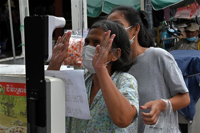 Đo thân nhiệt nhằm ngăn ngừa sự lây lan của dịch COVID-19 trước khi vào chợ tại Phnom Penh, Campuchia, ngày 24/5/2021. Ảnh: AFP/TTXVN