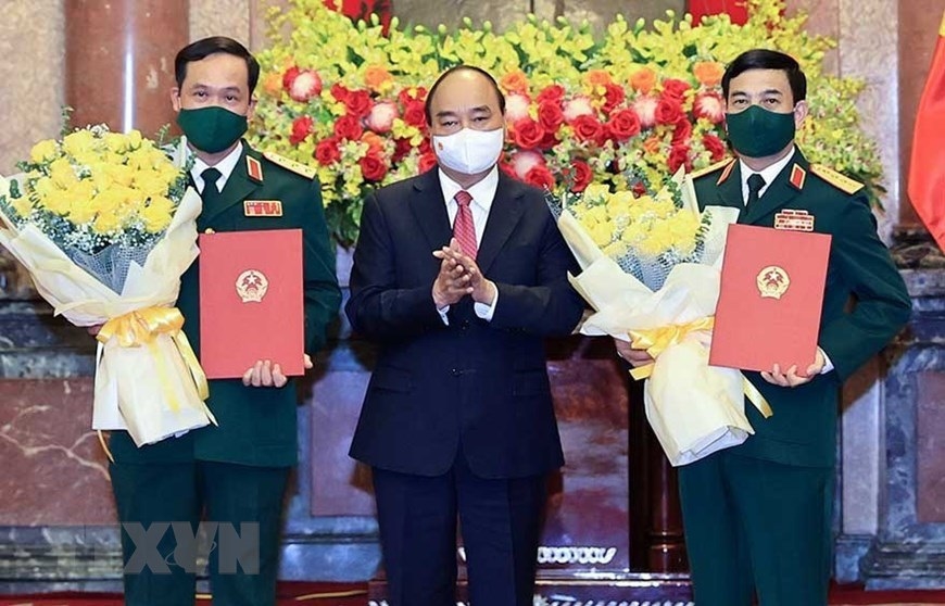 Chủ tịch nước Nguyễn Xuân Phúc trao quyết định thăng quân hàm, hoa chúc mừng Bộ trưởng Quốc phòng Phan Văn Giang (phải) và Thứ trưởng Vũ Hải Sản. Ảnh: TTXVN