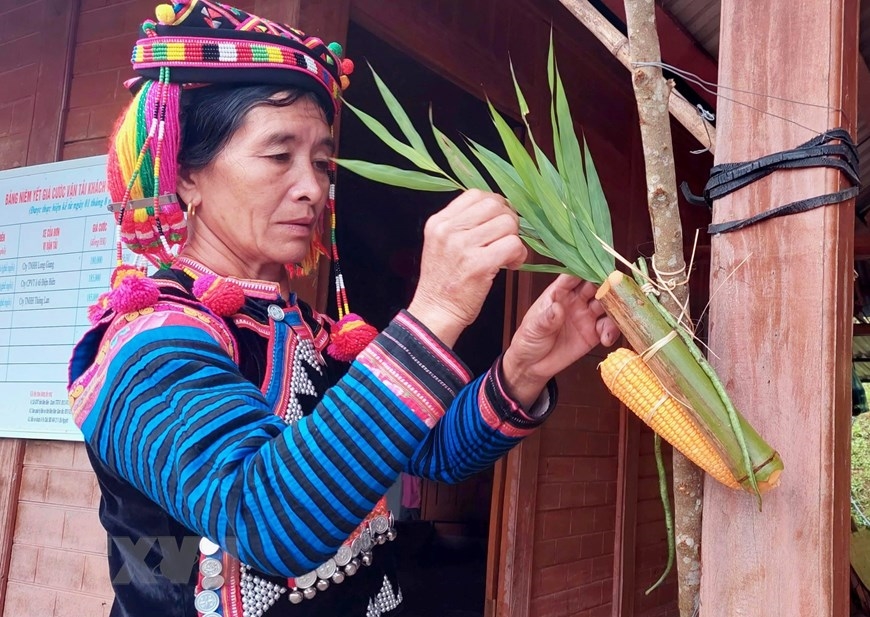 Người phụ nữ Hà Nhì trong trang phục truyền thống ở bản Tả Cố Khừ (xã Sín Thầu, huyện Mường Nhé, tỉnh Điện Biên) chuẩn bị cho lễ cúng trước thềm nhà. Ảnh: TTXVN