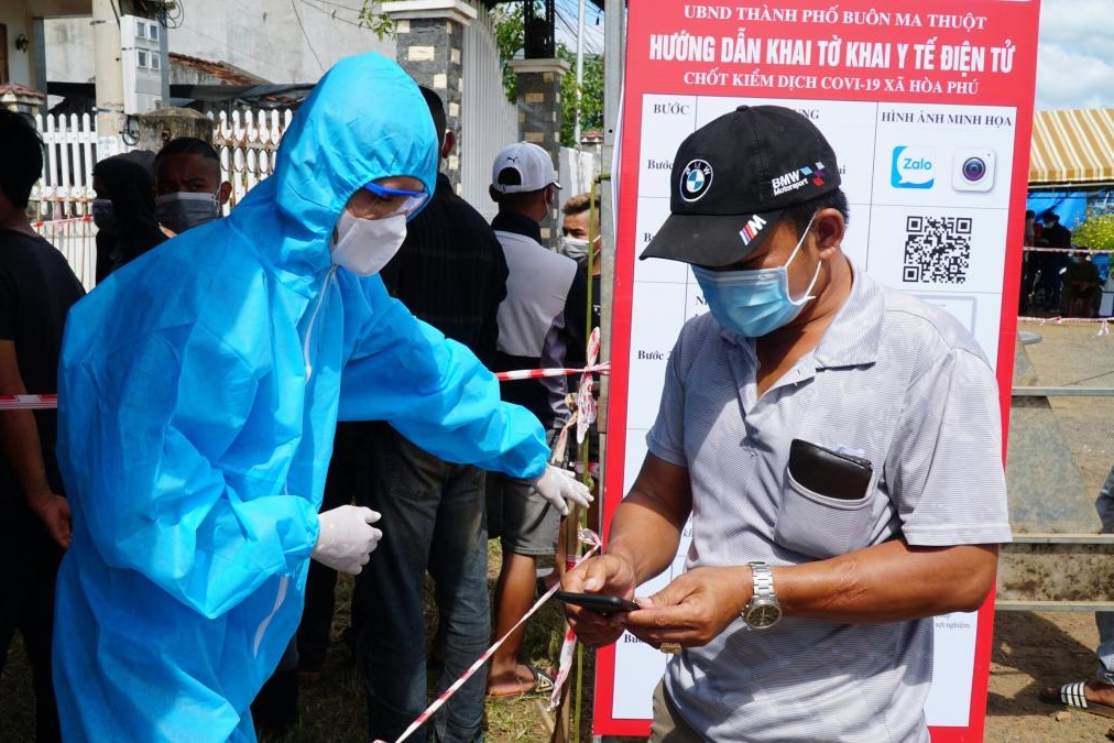Nhân viên y tế hướng dẫn người dân khai báo y tế điện tử tại Chốt kiểm soát phòng, chống dịch trên Quốc lộ 14 đoạn qua xã Hòa Phú (TP. Buôn Ma Thuột) 