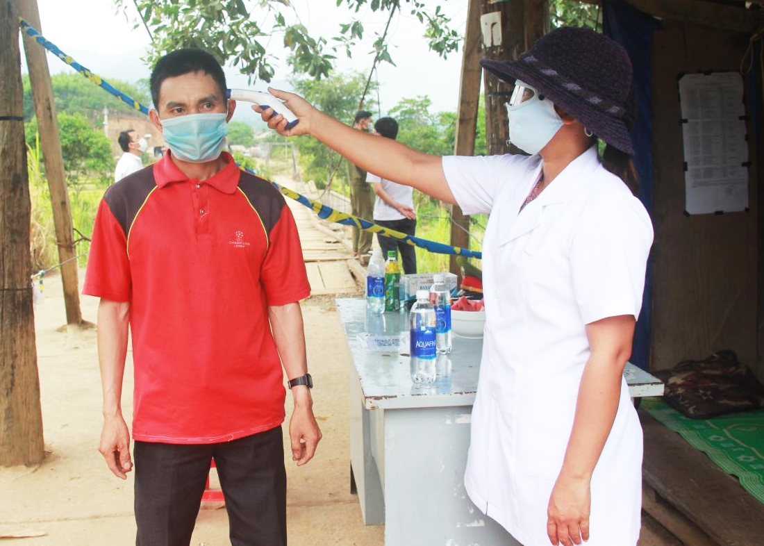 Nhân viên y tế kiểm tra thân nhiệt người dân qua chốt kiểm soát phòng, chống dịch trên đường Đông Trường Sơn, đoạn qua xã Cư San, huyện M'Drắk