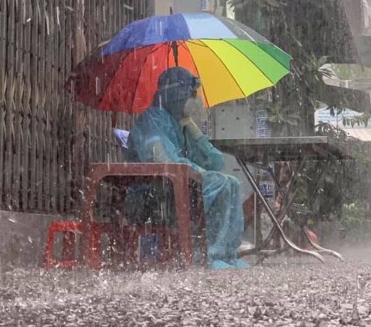 Hình ảnh một tình nguyện viên nơi tuyến đầu ngồi che dù trong cơn mưa. Họ đang chiến đấu vì chúng ta, vậy chúng ta đã làm gì?