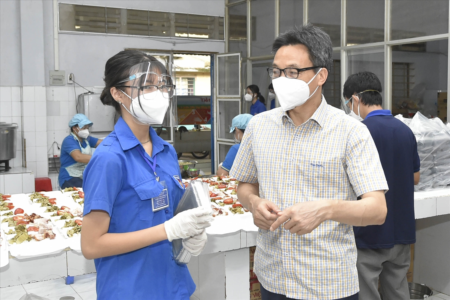Phó Thủ tướng Vũ Đức Đam trò chuyện với một tình nguyện viên là học sinh lớp 11 tại bếp ăn ở Trường tiểu học Lương Thế Vinh (phường Bình Thọ, TP. Thủ Đức)