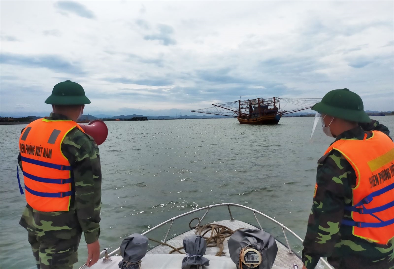 Cán bộ chiến sỹ Biên phòng Quảng Bình kêu gọi, hướng dẫn tàu, thuyền vào neo đậu tại bến thuyền, cảng cá đảm bảo an toàn. Ảnh: TTXVN 