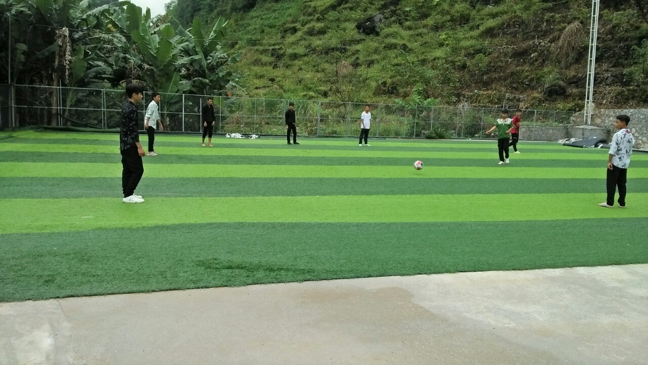 Các bạn thiếu niên ở Sủng Máng tập luyện bóng trong sân cỏ nhân tạo