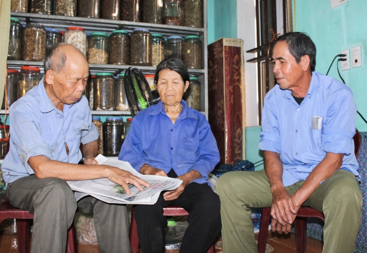 Ông Nguyễn Văn Lực (bên trái) tư vấn, trao đổi với người dân về mô hình phát triển kinh tế đăng trên báo