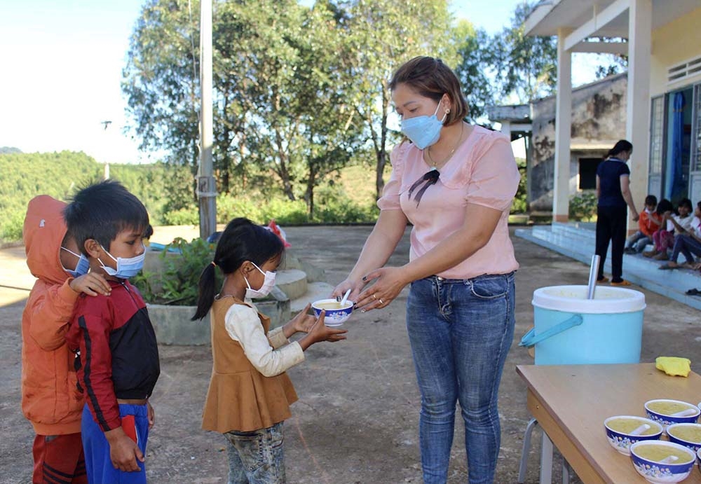 Học sinh Trường Tiểu học Hà Ra số 2, điểm trường làng Đê Kôn, nhận bát cháo đầy đủ chất dinh dưỡng từ tay chị Hà Thị Thanh Việt
