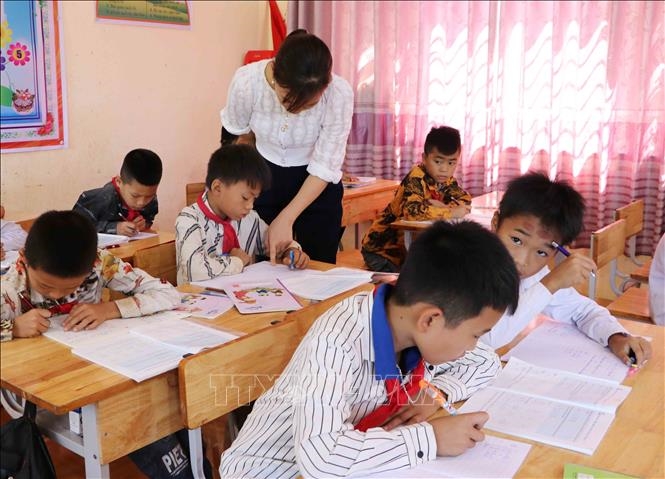Giáo viên Trường Tiểu học Đoàn Kết, huyện Phong Thổ (Lai Châu) hướng dẫn học sinh viết chữ. Ảnh: Việt Hoàng/TTXVN