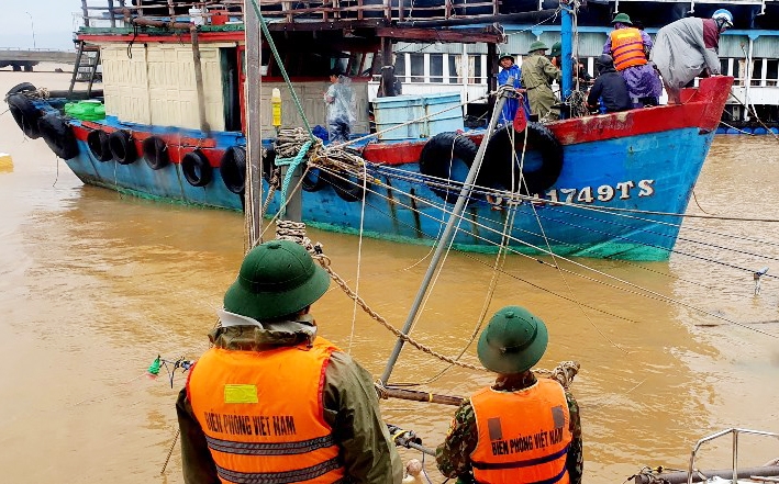 Cán bộ, chiến sĩ Đồn Biên phòng Ròon, BĐBP Quảng Bình giúp ngư dân neo buộc tàu khi nước lũ dâng cao, sóng lớn