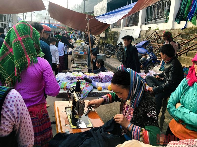 Một quầy sửa quần áo đắt khách giữa chợ, khách đứng xếp hàng chờ lấy ngay