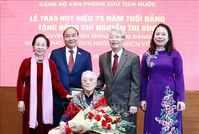 Chủ tịch nước Nguyễn Xuân Phúc và các đại biểu tại lễ trao tặng Huy hiệu 75 năm tuổi Đảng cho bà Nguyễn Thị Bình. Ảnh: TTXVN