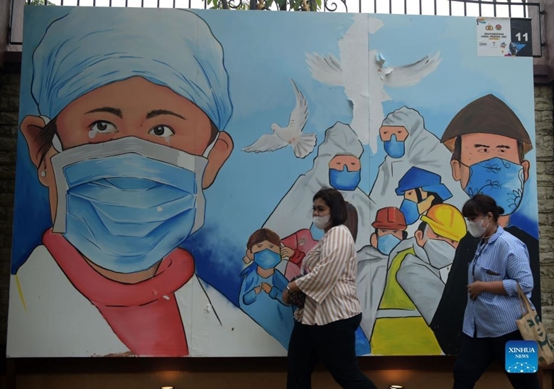 Người dân đi ngang qua một bức tranh mô tả nỗ lực của các nhân viên y tế chống lại COVID-19 ở Jakarta, Indonesia, ngày 16/12/2021. Đây cũng là thời điểm Indonesia công bố phát hiện trường hợp đầu tiên nhiễm biến thể Omicron là một nhân viên dọn dẹp tại một bệnh viện điều trị COVID-19 ở thủ đô Jakarta. (Ảnh: Xinhua)