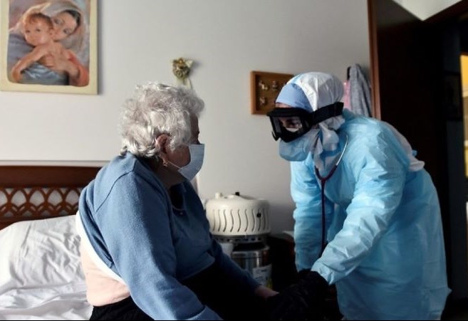 Một bác sĩ mặc đồ bảo hộ thăm khám một người bệnh Covid-19 điều trị tại nhà ở Bergamo - tâm chấn của đợt bùng phát dịch ở Italia năm 2020. Ảnh: Reuters 