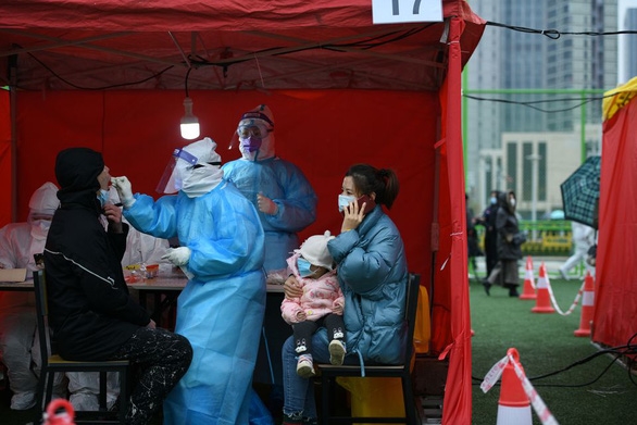 Nhân viên y tế mặc đồ bảo hộ đang xét nghiệm COVID-19 cho người dân tại một trung tâm thể thao ở Thiên Tân, Trung Quốc ngày 21/11 - Ảnh: Reuters