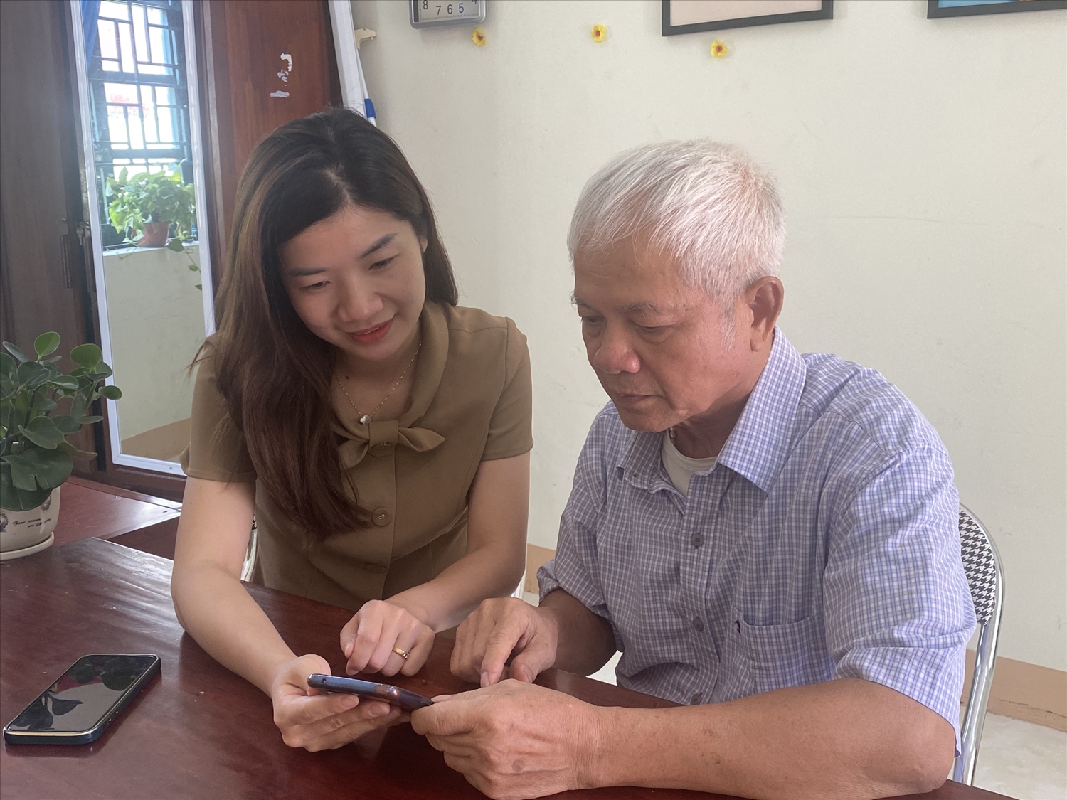 Cán bộ hướng dẫn cài đặt sổ tay đảng viên điện tử cho người cao tuổi ở thị trấn Đình Cả, huyện Võ Nhai.
