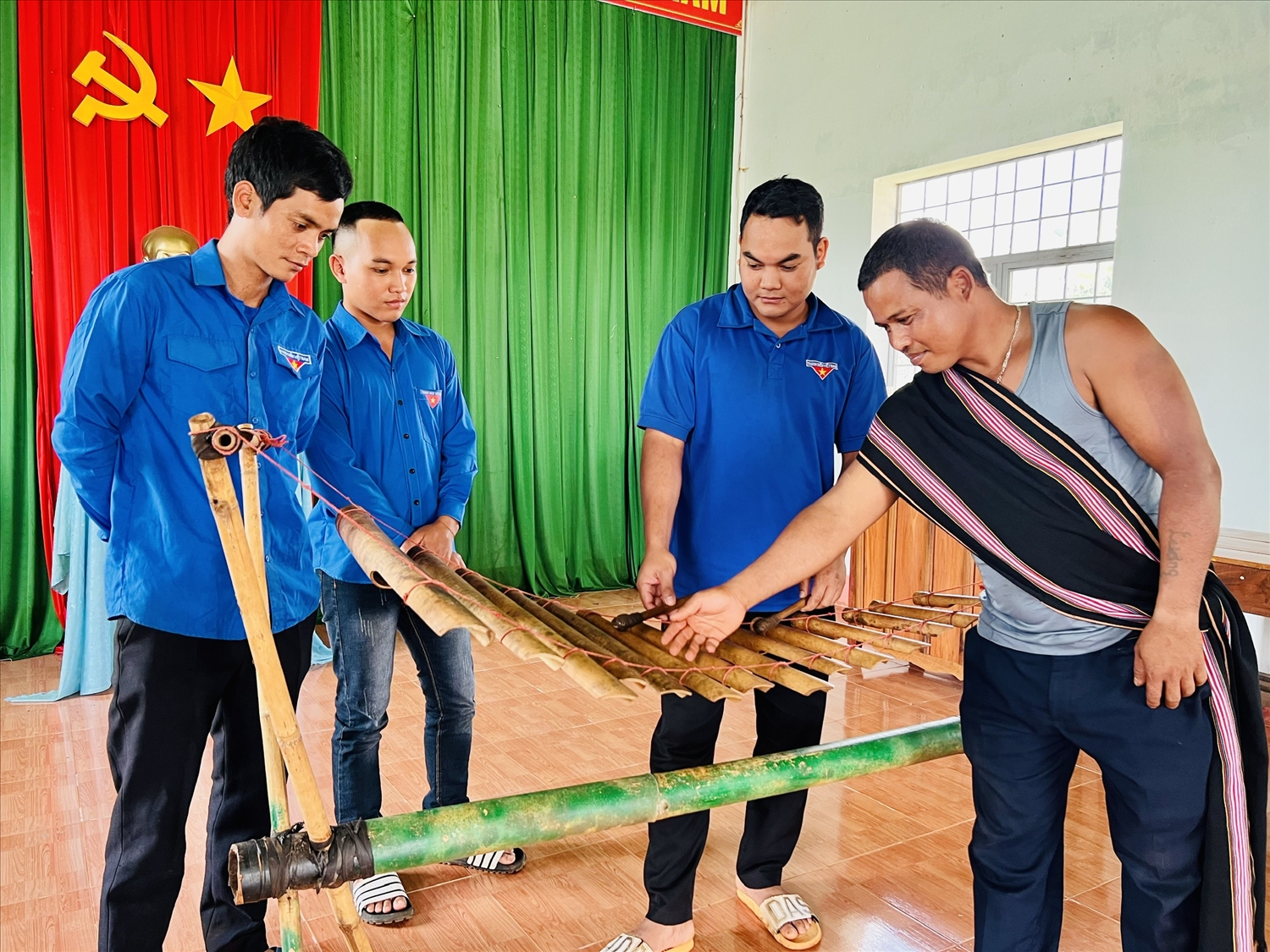 Anh Kpuih Dyui - Chủ nhiệm Câu lạc bộ đàn T’rưng làng Ấp (xã Ia Kriêng, huyện Đức Cơ) hướng dẫn học viên cách chơi nhạc cụ dân tộc