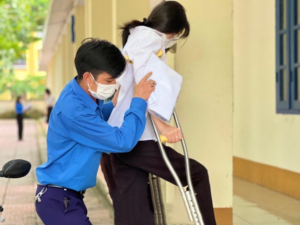 Tại điểm thi trường THPT Tiên Yên, các bạn tình nguyện viên hỗ trợ các thí sinh bị khuyết tật và bị thương khiến việc di chuyển khó khăn