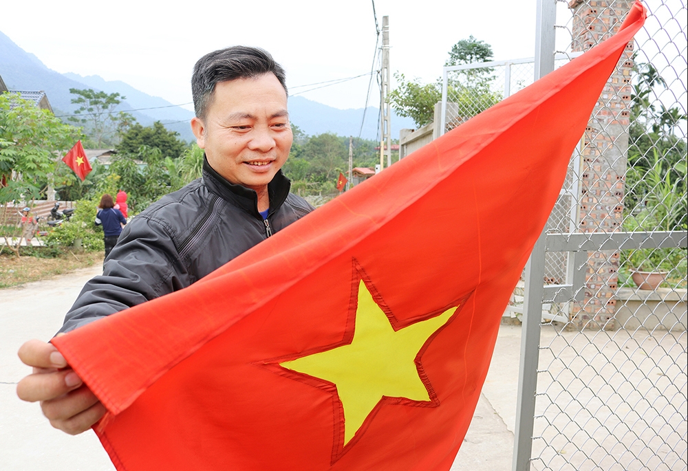 Ông Nguyễn Văn Tuấn - giáo dân họ giáo Hương Chan, xã Hương Lung, chuẩn bị treo cờ Tổ quốc trước nhà