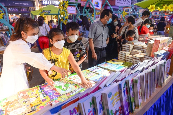 Trẻ em chọn mua sách tại đường sách Nguyễn Huệ tối 5-2 - Ảnh: BTT