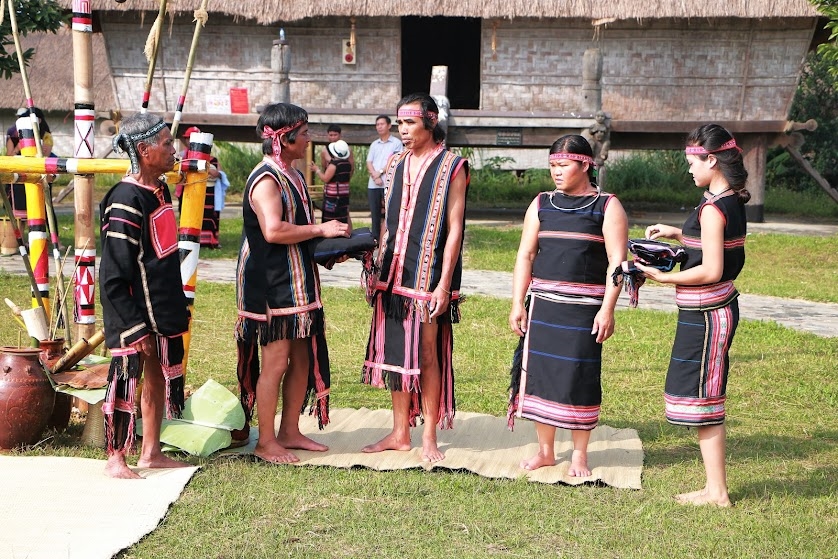 Nghi thức tặng trang phục truyền thống cho bố mẹ của vợ chồng trẻ người Gia Rai trước sự chứng kiến của già làng và dân làng. 