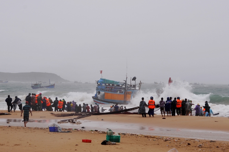Các lực lượng cứu hộ cùng ngư dân tham gia kéo những tàu cá ở xã An Phú (TP. Tuy Hòa) bị chìm vào bờ.